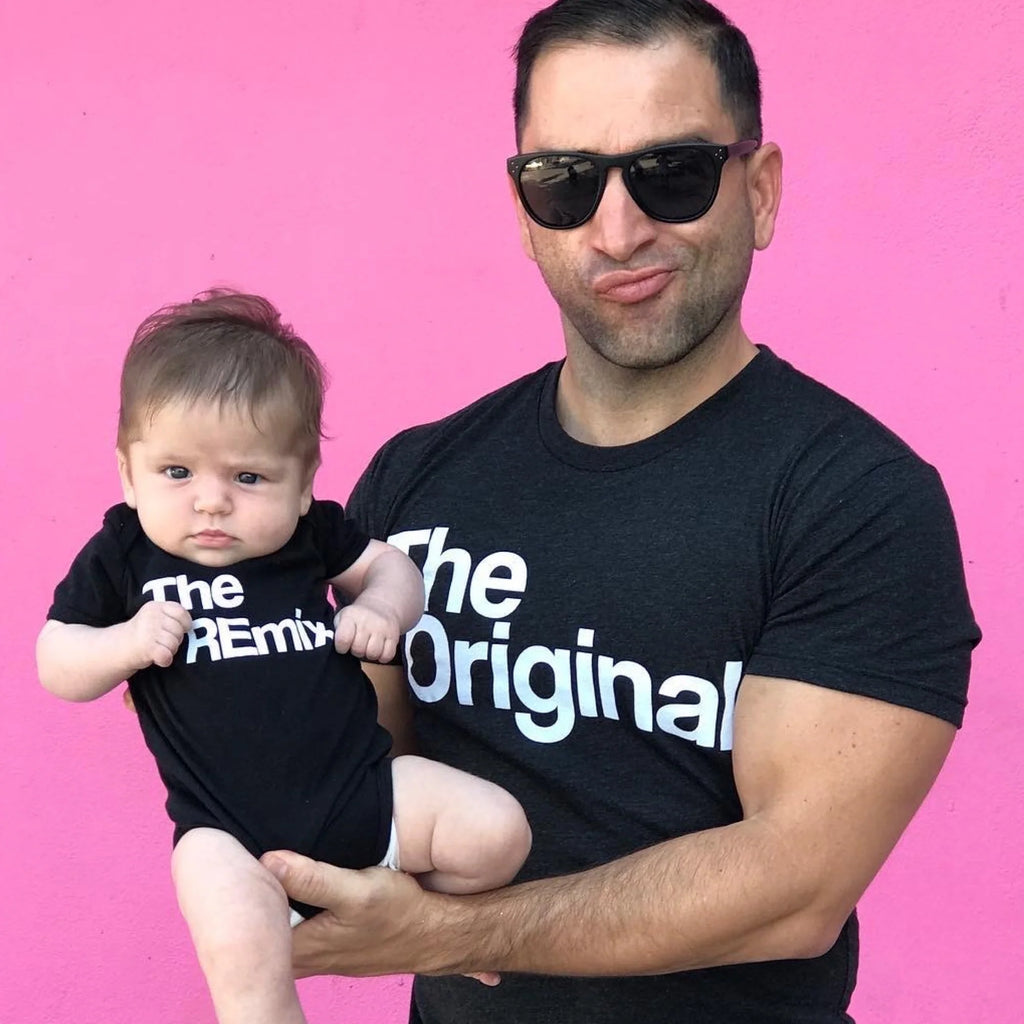 dad and baby girl behind a pink back drop wearing matching shirts that are screen print designs that says the original the remix baby onesie and unisex adult shirt